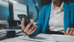 Giovane donna che controlla lo smartphone durante il lavoro