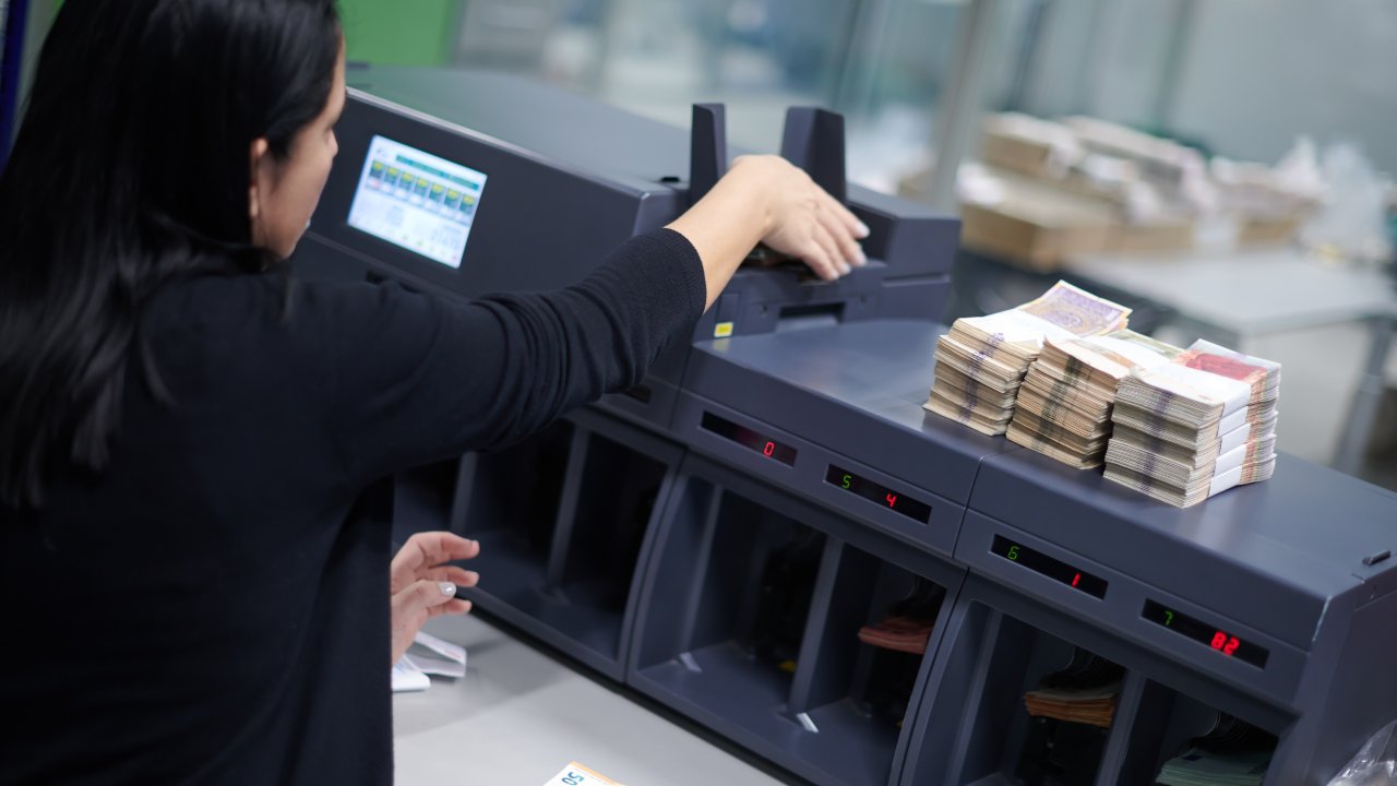 Impiegata di banca mette in ordine le mazzette di banconote